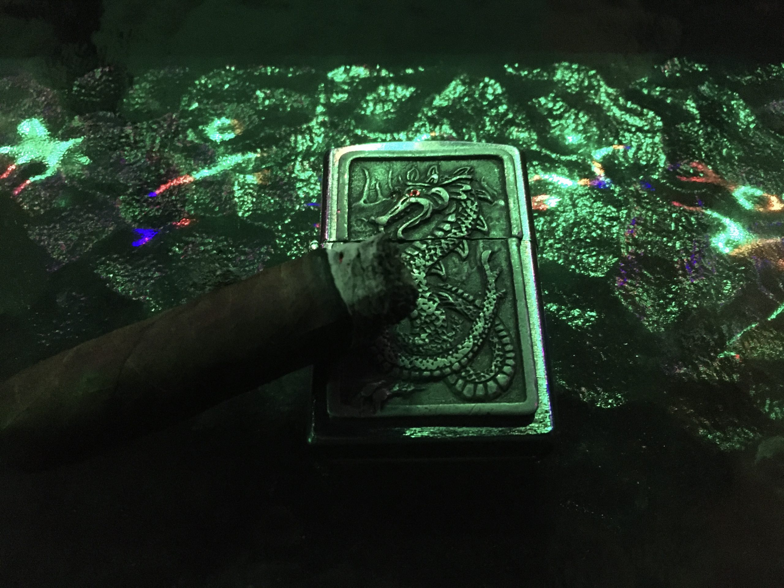 Dragon zippo lighter with lit cigar resting on it